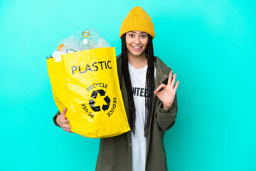 Teenager girl with braids holding a bag to recycle showing ok sign with two hands