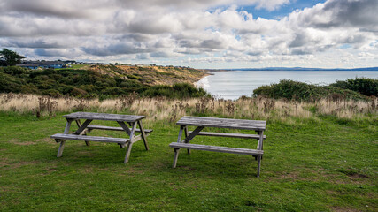Picnic benches with views of the cliffs and Naish Beach in Highcliffe, Dorset, England, UK