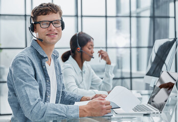 young man using a headset and computer in a modern office