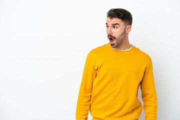 Fototapeta premium Young caucasian man isolated on white background doing surprise gesture while looking to the side