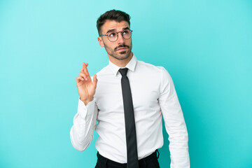 Business caucasian man isolated on blue background with fingers crossing and wishing the best