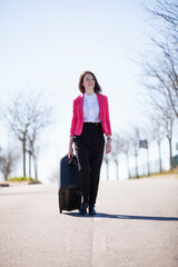 Walking confidently in the midst of the road, a woman pulls a suitcase with ease