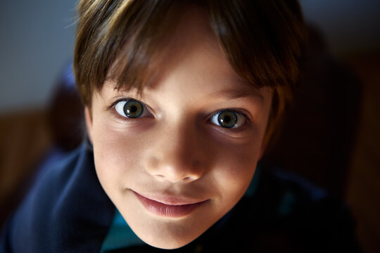 Young boy stare wide-eyed in shade room close up.