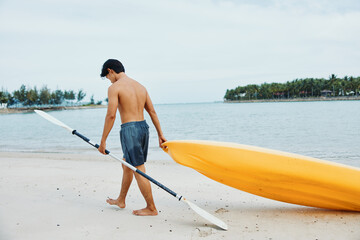 Serene Summer: A Happy Asian Man Enjoying Kayaking on a Tropical Beach