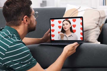 Long distance love. Man having video chat with his girlfriend via laptop at home - Powered by Adobe