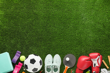 Naklejka premium Different sport equipment and sneakers on green grass, flat lay. Space for text