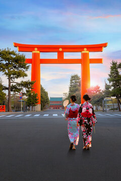 Young Japanese women in traditional Kimono dress at the Great Torii Gate of Heian Shrine in Kyoto, Japan