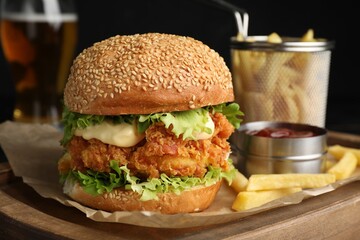 Delicious burger with crispy chicken patty, french fries and sauce on table, closeup