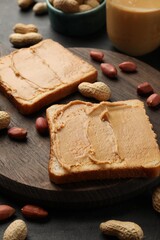 Tasty peanut butter sandwiches and peanuts on black table, closeup