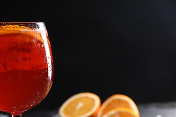 Glass of tasty Aperol spritz cocktail against black background, space for text