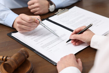 Lawyers working with documents at wooden table, closeup