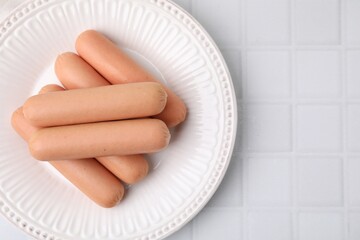Delicious boiled sausages on white tiled table, top view. Space for text