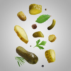Tasty pickled cucumbers, herbs and spices falling on light grey background