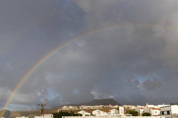 Rainbow descending on town of Agaete, Puerto de las nieves, Gran Canaria. Cliffs and white...