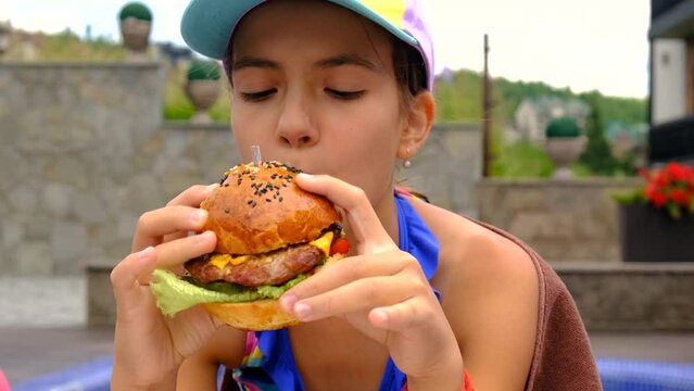 child eats a hamburger near the pool. Selective focus.