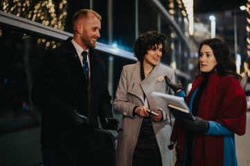 Smiling people holding documents on city street with festive lights at night.