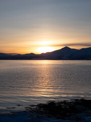 Sunset over the sea and mountains on the background at the time when the polar night has just ended.