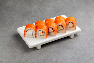Japanese Sushi roll Philadelphia spicy with salmon on a white stand, gray background
