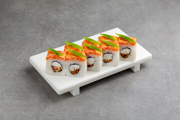 Japanese Sushi roll with salmon, green onions and fried onions on a white stand, gray background