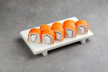 Japanese Sushi roll Philadelphia classic with salmon on a white stand, gray background