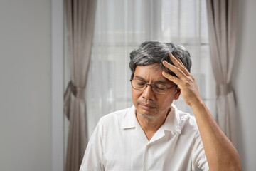 Senior asian man suffering from headache at home.