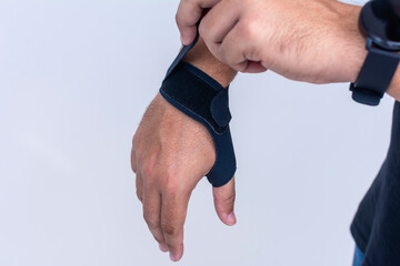A man adjusts the straps of an ultra-thin compression wrist and thumb brace for texting thumb...