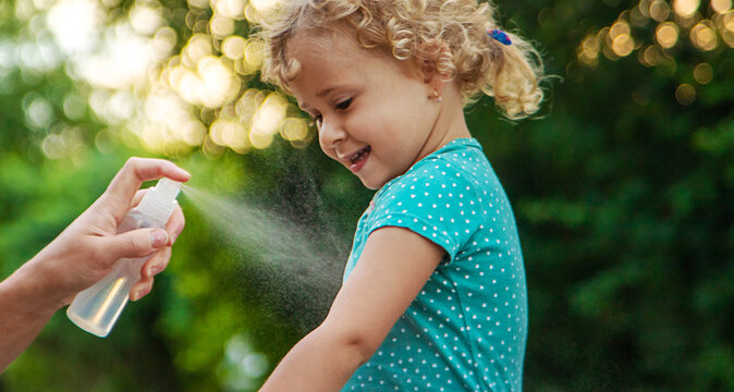 Mom sprays her child with mosquito repellent. Selective focus.