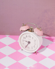 Vintage alarm bell clock in stylized pink checkered background, retro nostalgia, oldies greatest...