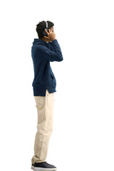 A man, full-length, on a white background, listening to music with headphones