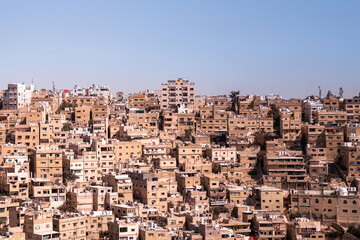 Fototapeta na wymiar 3x2 multiple high rise buildings in a Middle Eastern overpopulated neighbourhood. Flats are packed together like a puzzle with narrow alleyways. Warm sunny day blue sky. Amman, Jordan