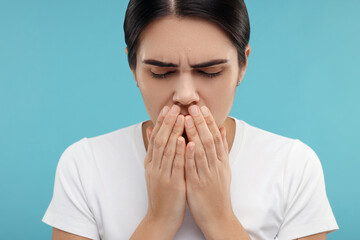 Woman coughing on light blue background. Cold symptoms