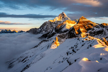 Mount Siguniang, Four Girls Mountain the Sacred Mountain in the East, National Geo-park of China, Sunset over a sea of clouds in the mountains with golden light touching snowy peaks