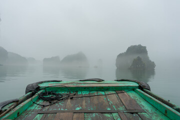 A tranquil boat journey through a mist-shrouded landscape with limestone karsts.