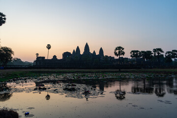 Silhouette of Angkor Wat at sunrise with reflections in water