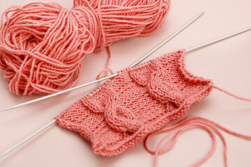 fragment of knitting with a pattern on the knitting needles next to the threads