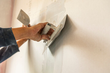 Old manual worker with wall plastering tools renovating house.