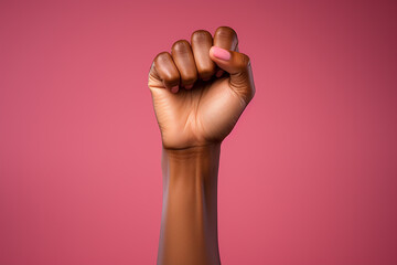 Raised fist of a black woman with nude manicure on a pink background, fight for women's rights, March 8