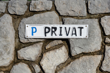 Detail of a gray stone wall with weathered privat parking sign