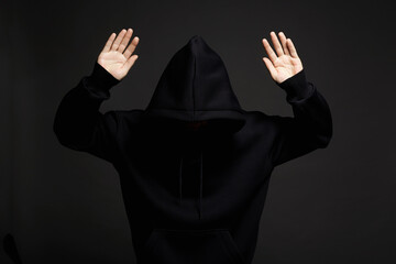 Boy in Black Hood. hooded man surrenders raising his hands up