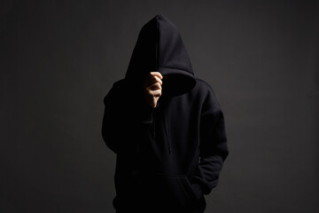 Man in Black Hood posing in dark studio. Boy in a hooded sweatshirt