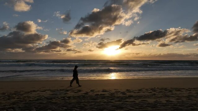 Chica paseando por la playa al atardecer