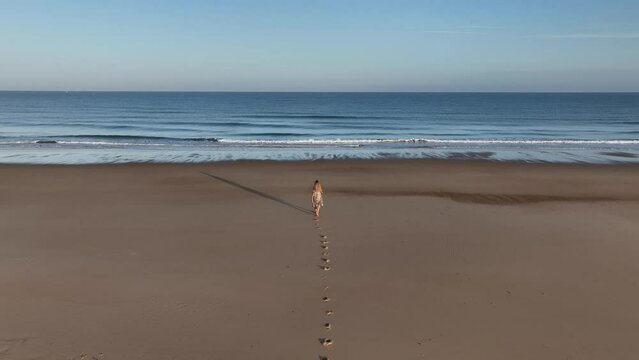 Chica paseando por la playa al amanecer de camino al mar