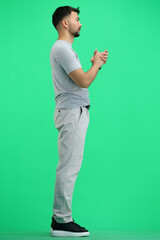 A man, full-length, on a green background, pleads