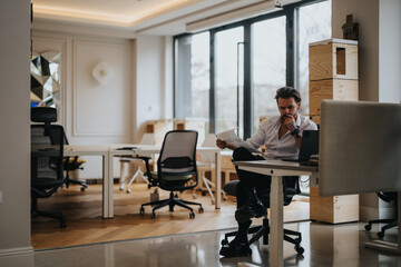 A young, professional entrepreneur deeply focused on work, analyzing papers at his clean and stylish office workspace.