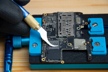 Technician is repairing Smartphone motherboard, circuit repair