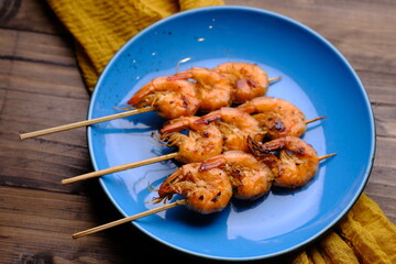 Sate Udang Bakar is Grilled Shrimp Satay. Made from prawns seasoned with honey, salt, olive oil, chilies. Served on a blue ceramic plate. Shrimp is a seafood. Indonesian food.