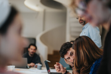 A man engages attentively with his team during a discussion in an airy, modern office space, depicting teamwork and collaboration.