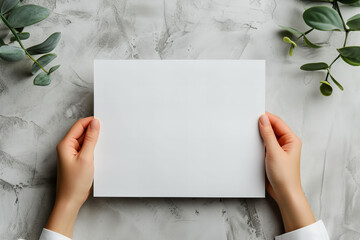 A woman holding a blank sheet of white paper or card with her hands isolated on grey background. An empty space for a text or a wish. 