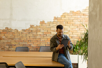 Smiling Man With Tablet in a Modern Brick-Walled Office
