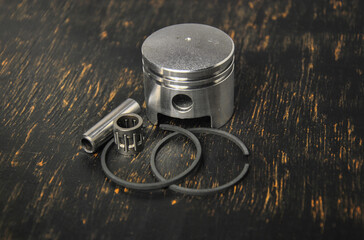 piston with piston rings on a dark background. piston from a garden tool engine. petrol tool repair.
